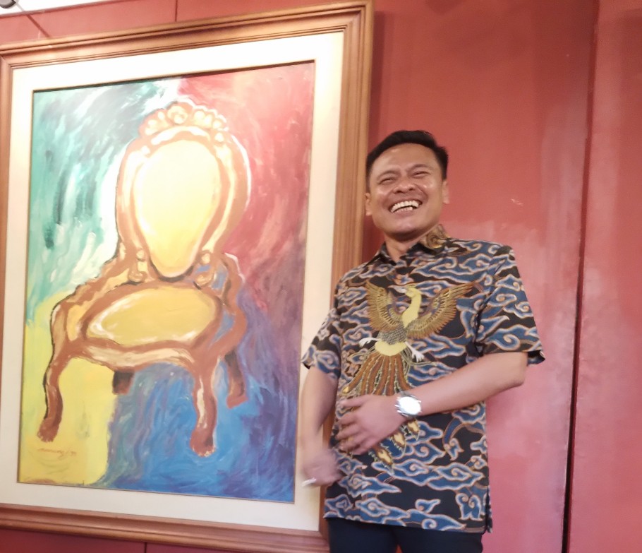 Arif Fathoni didamping lukisan sebuah kursi dalam sebuah kesempatan. /Foto: Amar