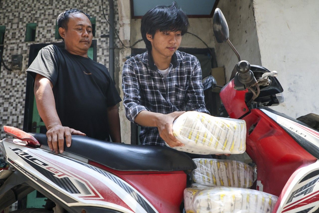 Ibra (kanan) saat membantu orang tuanya. (Kominfo Kota Surabaya)