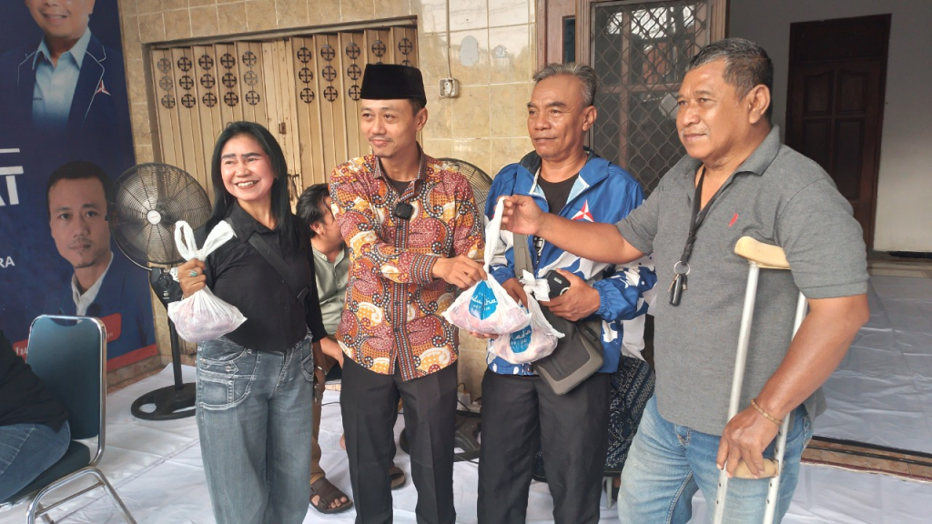 H. Junaedi, Sekretaris DPC Partai Demokrat Kota Surabaya (baju batik, beekopyah) saat menyerahkan daging kurban kepada perwakilan masyarakat. (Amar)