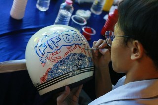 Salah satu peserta sedang mengekspresikan imajinasi mereka melalui coretan cat dan kuas ke atas helm polos yang disediakan oleh panitia pada Helmet Art Painting Workshop yang diadakan FIFASTRA di Booth FIFGROUP Jelajah Kota saat gelaran Festival Kota Lama