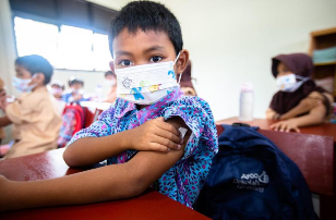 Seorang murid kelas 1 SDN 003 Bintan Timur, Provinsi Riau, menerima imunisasi di masa Bulan Imunisasi Anak Nasional. (UNICEF/UN0647161/Clark)_